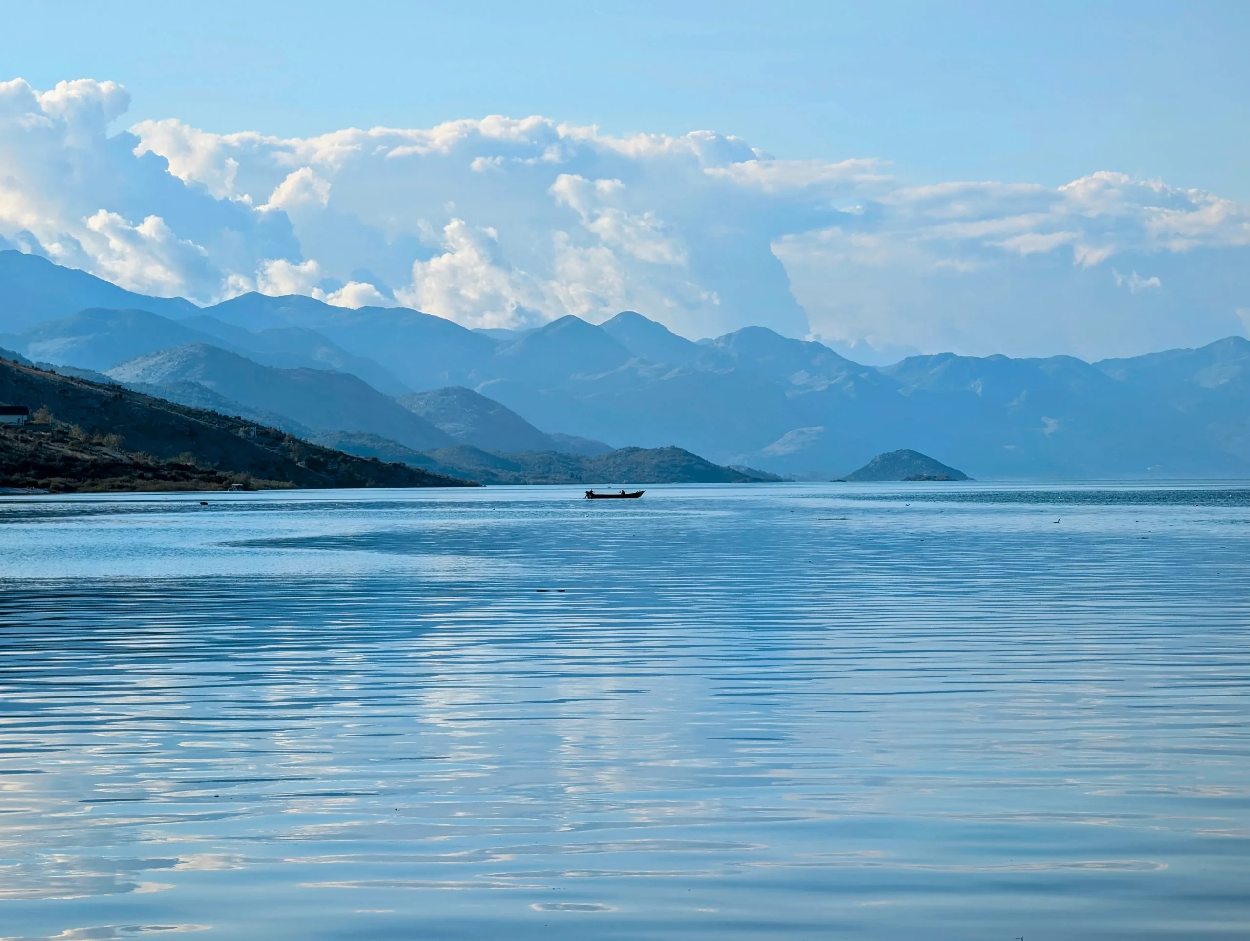 Scenic view of Lake Shkoder with mountains in the background and calm, reflective water.